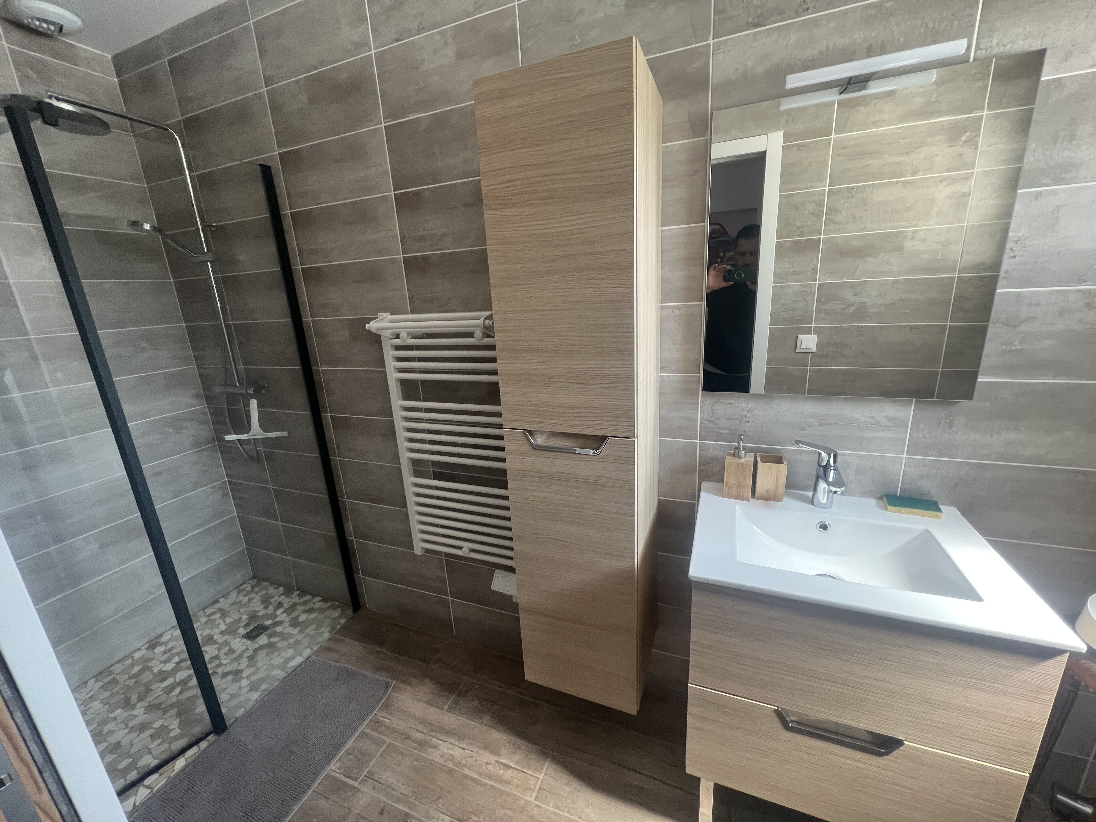 Une salle de bain moderne équipée d’une douche, d’un lavabo et d’un miroir.