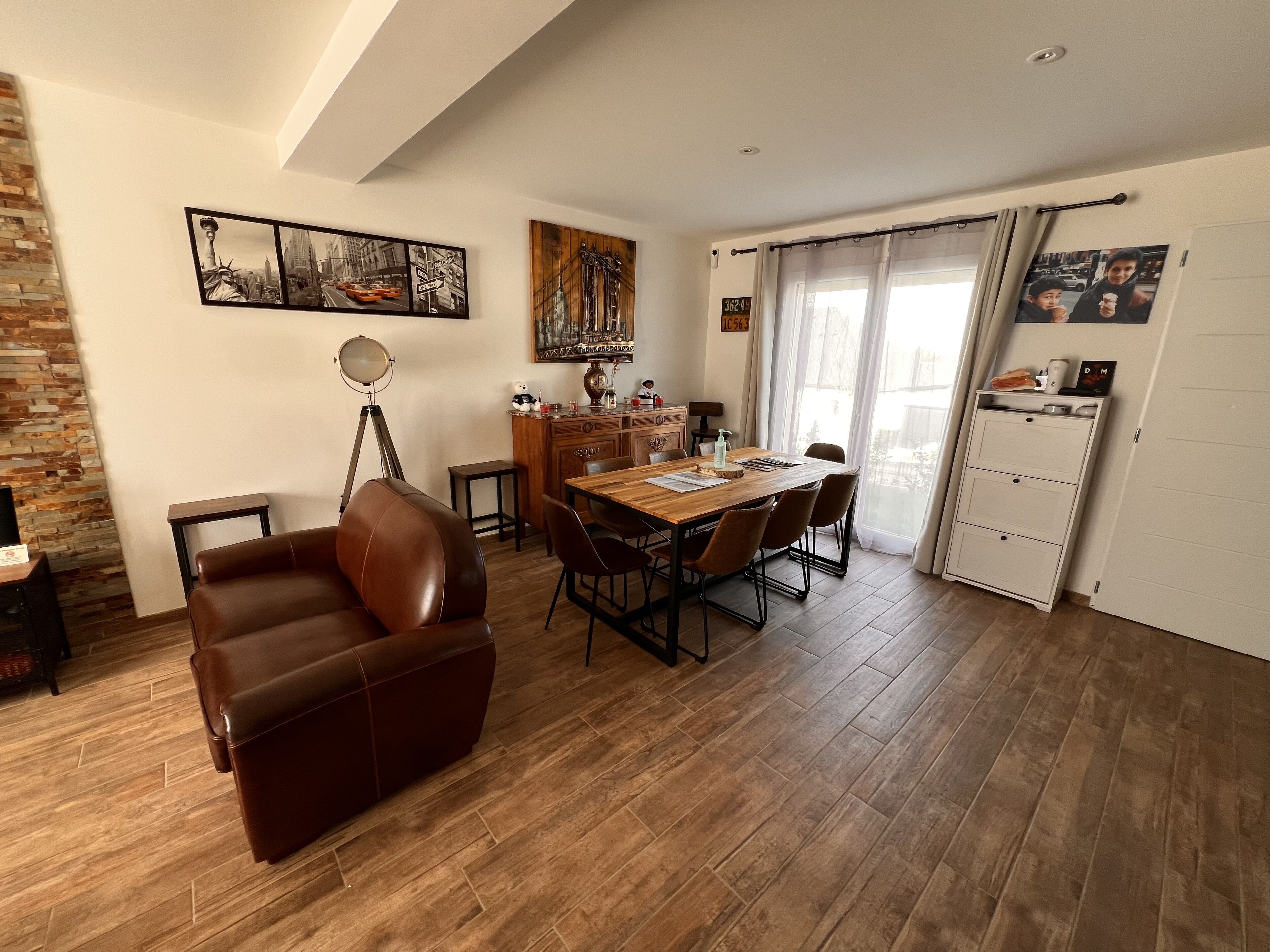Un coin repas avec une table et des chaises en bois, un canapé en cuir et un lustre.