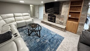 A living room with a white leather sofa, a blue rug, a fireplace, and a TV mounted on the wall. - DEER CAVERN secluded 4 bedroom 2 bath house East Sandy base of Alta & Snowbird (Sandy)