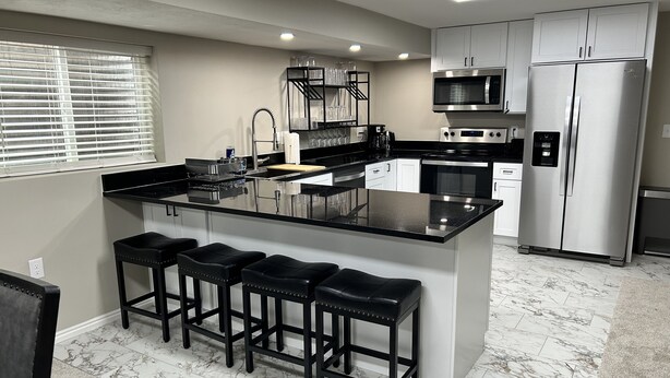 A modern kitchen with a central island, stainless steel appliances, and a marble floor. - DEER CAVERN secluded 4 bedroom 2 bath house East Sandy base of Alta & Snowbird (Sandy)