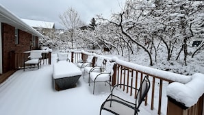 A snow-covered outdoor seating area with a wooden deck and metal chairs. - DEER CAVERN secluded 4 bedroom 2 bath house East Sandy base of Alta & Snowbird (Sandy)