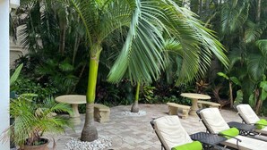 Eine Terrasse mit Lounge-Möbeln, einer Palme und einem Steintisch.