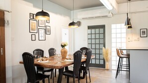 A dining area with a wooden table set for six, black chairs, and pendant lighting. - The Golden House @ Suvarnabhumi: Escape City Chaos, Gateway to Bangkok & Beyond! (Lat Krabang)