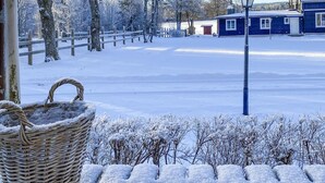 Un paysage enneigé avec une clôture en bois, une maison et un panier en osier rempli de neige.