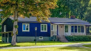 Une maison à deux étages, à la façade bleue, dotée d’un porche et d’un escalier extérieur menant à l’entrée.