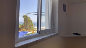 Une pièce dotée d’une grande fenêtre donnant sur une plage et la mer.