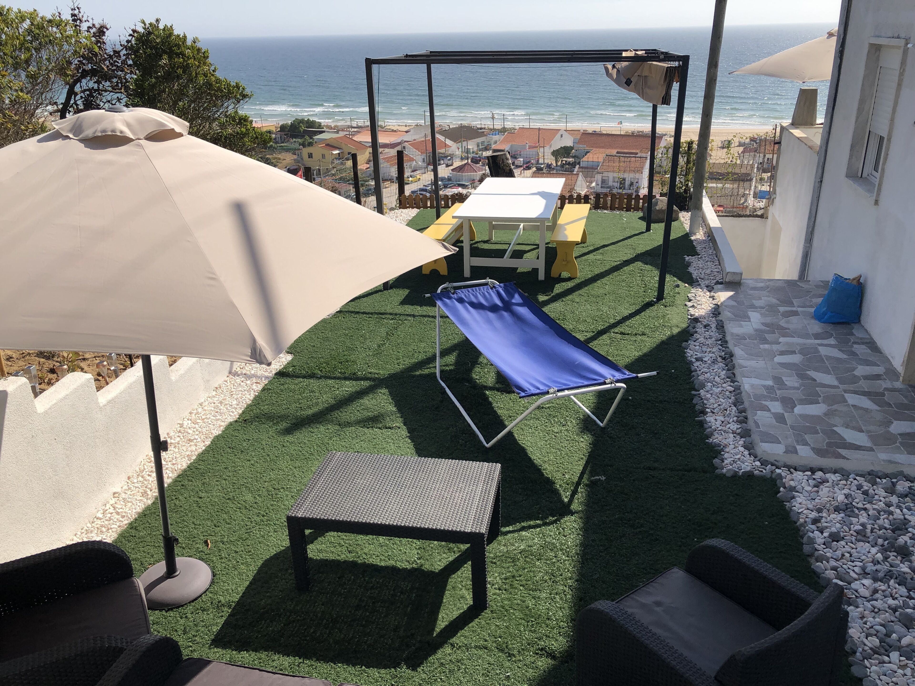 Un patio con un columpio, una mesa y una silla de relax.