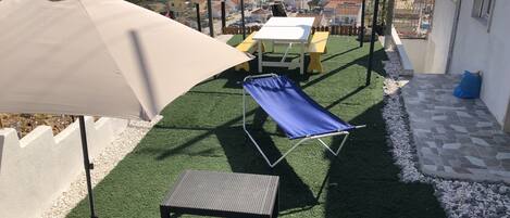 Un patio con un columpio, una mesa y una silla de relax.