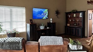 A living room with a television, a bookshelf, and a window with blinds.