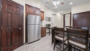 Una cocina con armarios de madera, un refrigerador de acero inoxidable, una mesa de comedor con sillas y un ventilador de techo.