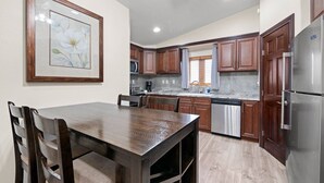 Una cocina con armarios de madera, un refrigerador de acero inoxidable y una mesa de comedor con sillas.