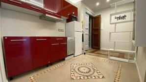 Une cuisine moderne avec des meubles rouges, un réfrigérateur blanc et un sol à motifs.