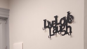 Un mur blanc orné d’un panneau décoratif noir sur lequel on peut lire : « Vivez, aimez, riez ».