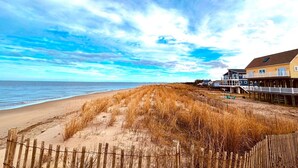 A beach with a wooden fence, a sandy path, and houses with wooden decks.