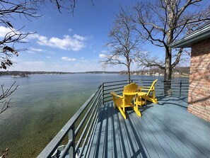 Une terrasse avec une table et des chaises, donnant sur une étendue d’eau et une côte lointaine.