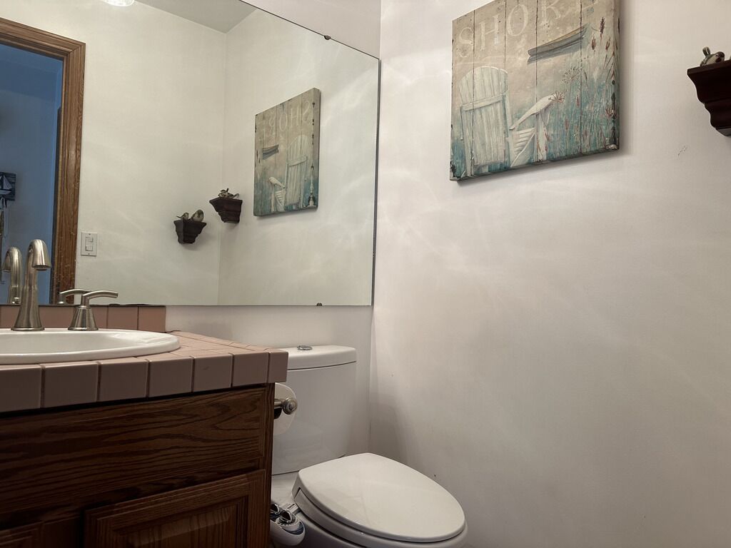A bathroom with a sink, toilet, and two wall-mounted paintings.