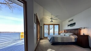 A bedroom with a large window, a bed, a ceiling fan, and a view of a dock and water. - Experience lakefront luxury with spectacular views on Lake James, Indiana! (Angola)