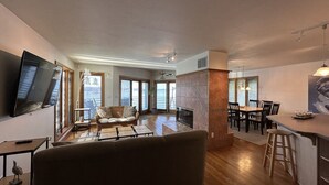A spacious living area with a sofa, a TV, and a fireplace. There is a dining area with a table and chairs. - Experience lakefront luxury with spectacular views on Lake James, Indiana! (Angola)