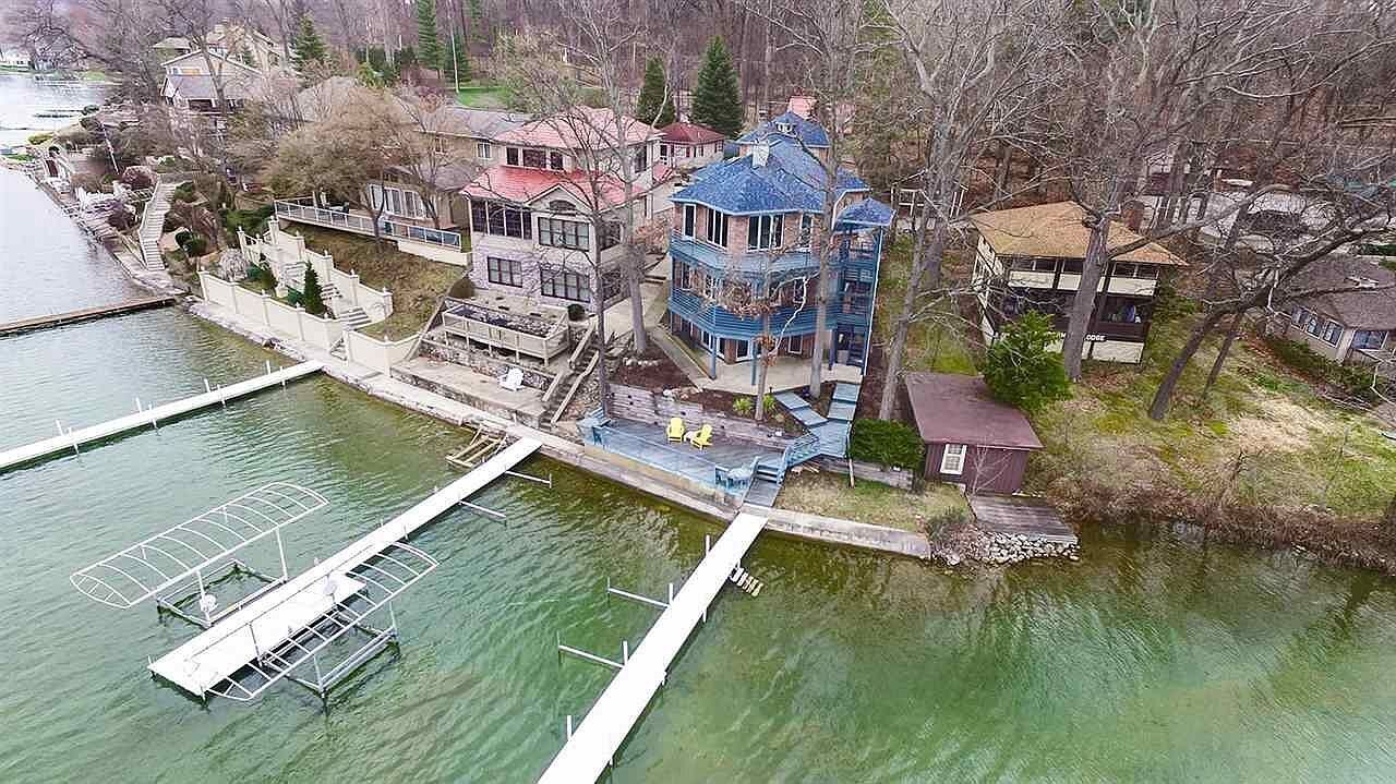Propiedad frente al agua con varias construcciones, un muelle y un barco pequeño.