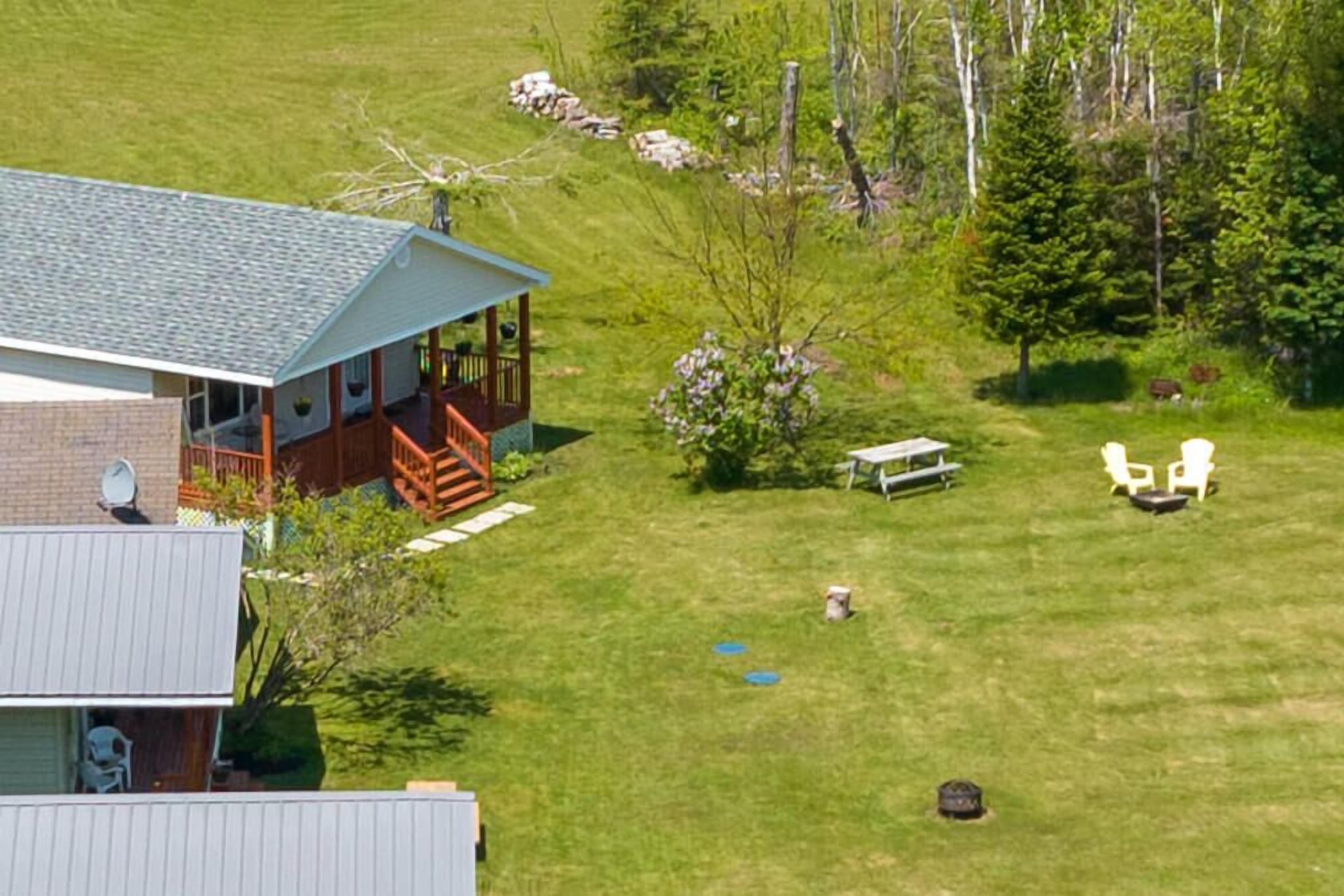 A house with a covered porch, a lawn, and a picnic table.