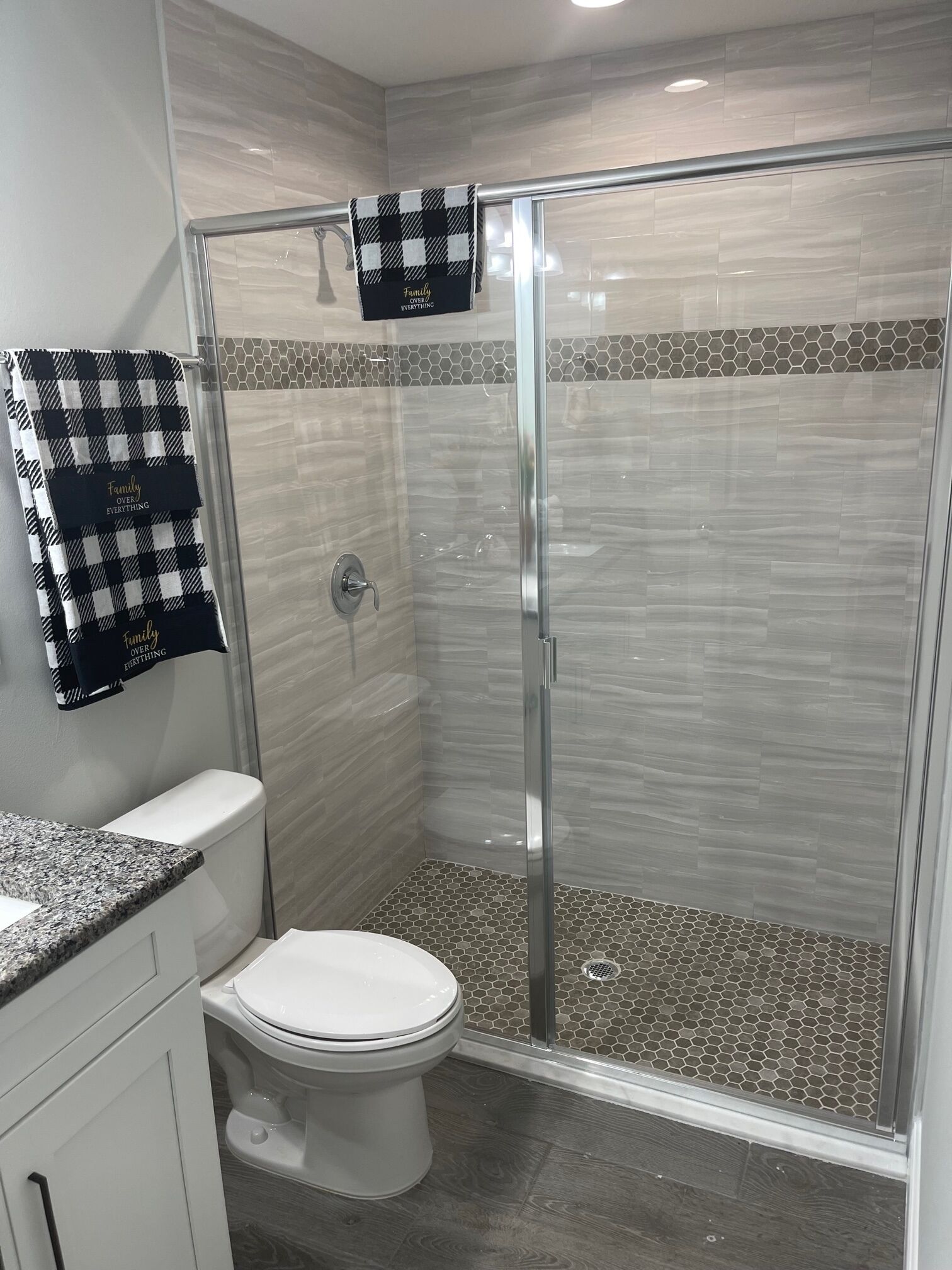 A modern bathroom with a glass-enclosed shower, a toilet, and a vanity with a granite countertop.
