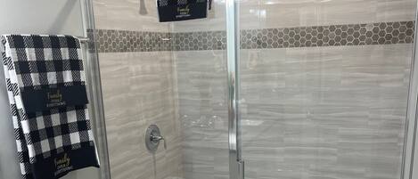 A modern bathroom with a glass-enclosed shower, a toilet, and a vanity with a granite countertop.