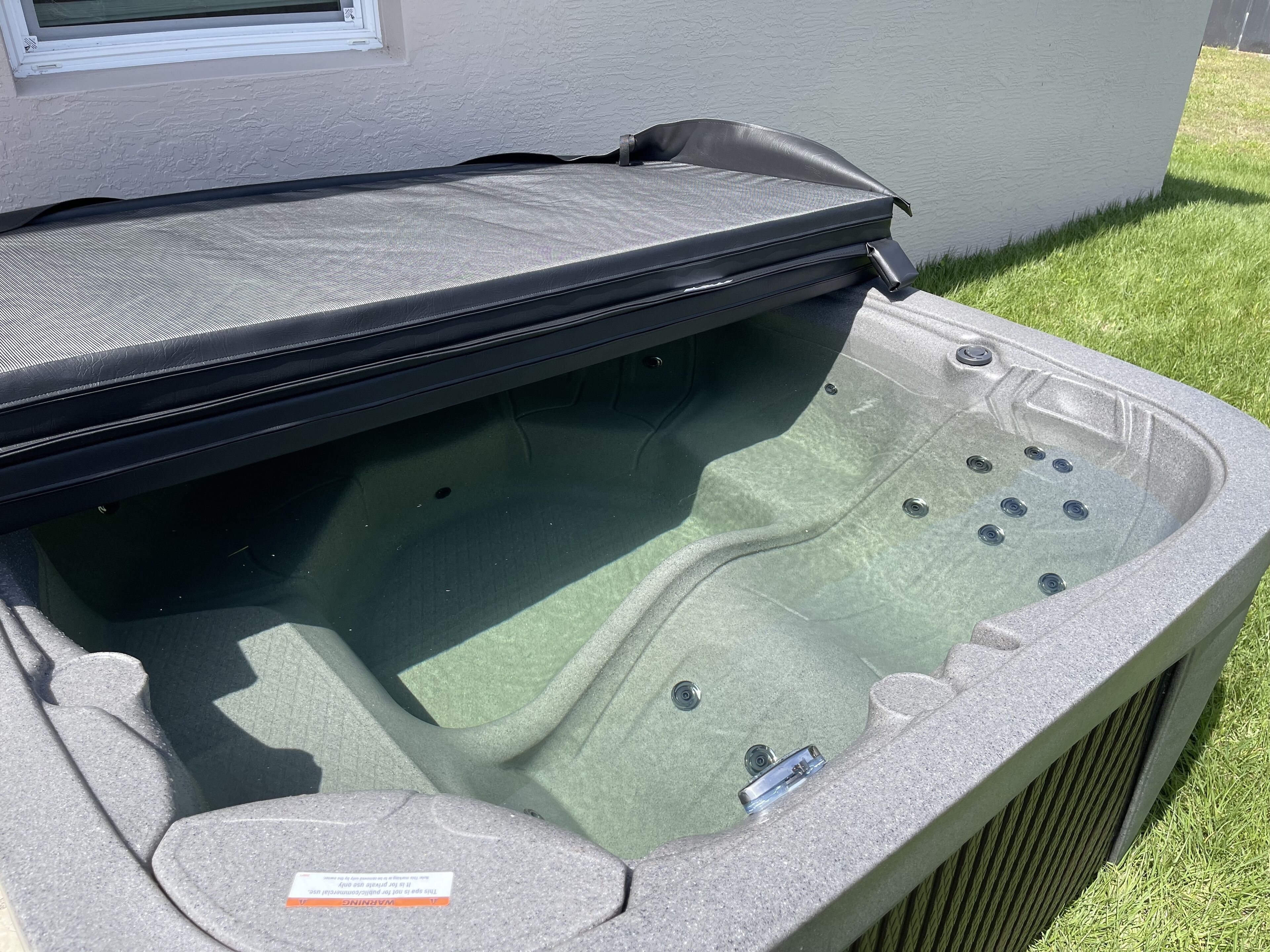 Un jacuzzi con tapa, chorros integrados y un panel de control.
