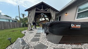 A patio area with a covered grill, outdoor furniture, and a pathway of stepping stones. - New modern 3-bed 2 bath house with smart TV's in every room, WIFI, and hot tub (Fort Pierce)