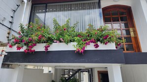 Un edificio de dos pisos con un balcón decorado con plantas florecientes y una puerta de madera.