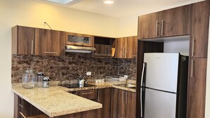 Una cocina moderna con armarios de madera oscura, encimera de granito y refrigerador de acero inoxidable.