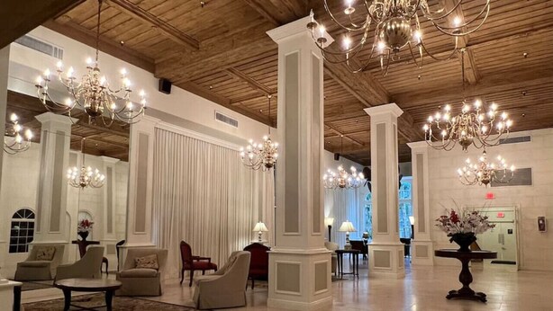 A spacious lobby with high ceilings, chandeliers, and seating areas.