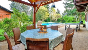 A covered outdoor seating area with wicker furniture and a pool in the background.