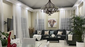 A modern living room with a glass dining table, a black sofa, and a chandelier. - Casa de la Playa (Puerto Plata)