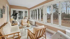 A sunroom with large windows, wicker furniture, and a treadmill. - 5 bdrm Victorian, built in 1881-With 21 rooms, on a hill on 4 VERY private acres (New Windsor)