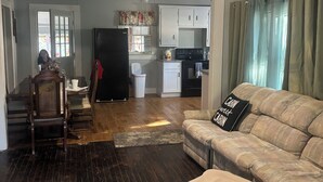 A living room with a sofa, a dining area with a table and chairs, a kitchen with cabinets and appliances, and a staircase leading to another level. - Cute cottage in a rural setting (Clemmons)