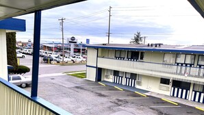 A motel with a parking lot, a view of the street, and a building with a blue awning. - Royal A Motel (Auburn)