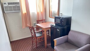A compact room with a kitchenette, a dining table with two chairs, a sofa, and a patterned floor. - Royal A Motel (Auburn)