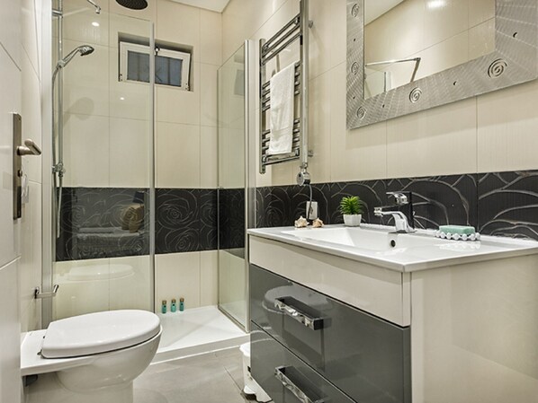 A modern bathroom with a glass shower enclosure, a white toilet, a vanity with a sink, and a mirror.