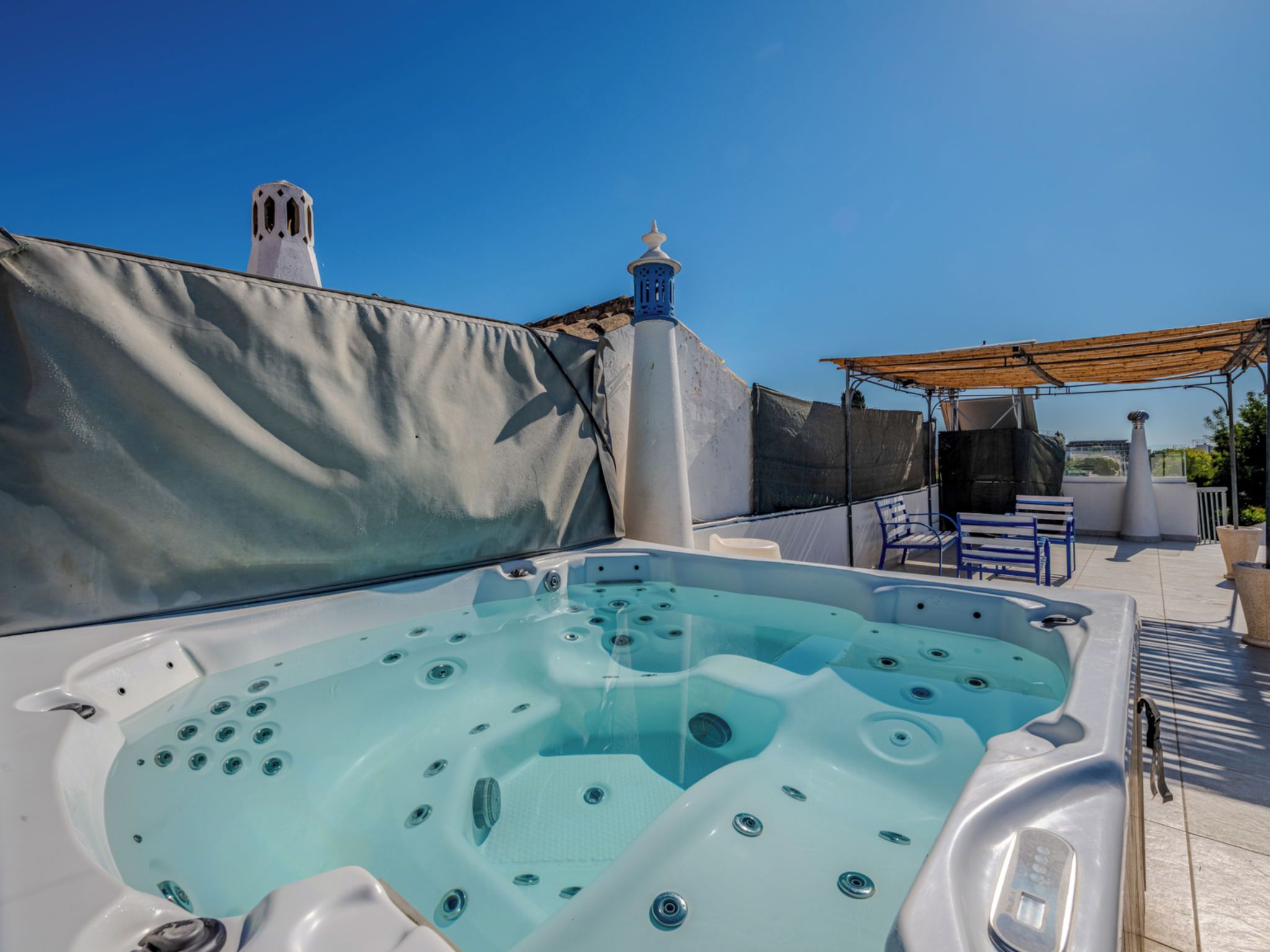 A rooftop with a hot tub, a pergola, and outdoor seating.