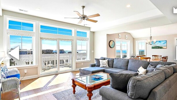 A spacious living room with a large gray sectional sofa, a glass coffee table, and a ceiling fan. - Bay and Beach Views Sunsets! Elevator, Heated Saltwater Pool open May 23, 2026.
 (Beach Haven)