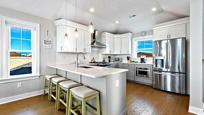 A modern kitchen with white cabinets, stainless steel appliances, and a large island with bar stools. - Bay and Beach Views Sunsets! Elevator, Heated Saltwater Pool open May 23, 2026.
 (Beach Haven)