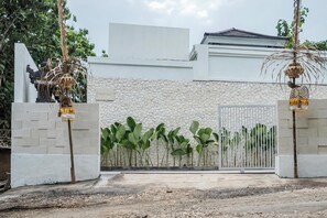 A gated entrance with a white wall and a stone-textured background. - Belvilla Serene Haven Nusa Dua Beach (Nusa Dua)