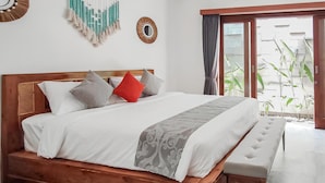 A wooden bed with a bench, white bedding, and decorative pillows. - Belvilla Serene Haven Nusa Dua Beach (Nusa Dua)