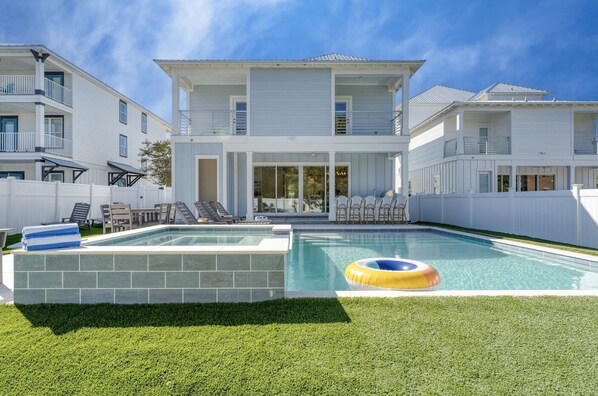 Une maison à deux étages avec une piscine, un patio couvert et une cour arrière clôturée.