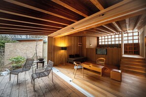 Ein modernes Interieur mit Holzdielen und Holzbalken, einem Sofa, einem Esstisch und einem Fernseher.