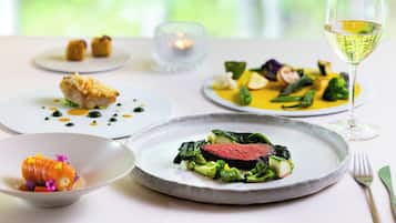 A dining table with various dishes and a glass of white wine.