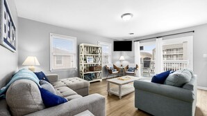 A modern living room with grey sofas, a coffee table, and a bookshelf.