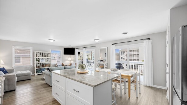 A modern kitchen with a central island, white cabinetry, and a dining area with a table and chairs.