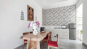 A modern kitchen with a geometric backsplash, a dining table with chairs, and a refrigerator. - Belvilla Calm Woods Pandawa Beach (Nusa Dua)