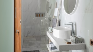 A modern bathroom with a large white sink, a round mirror, and a shower area. - Belvilla Calm Woods Pandawa Beach (Nusa Dua)